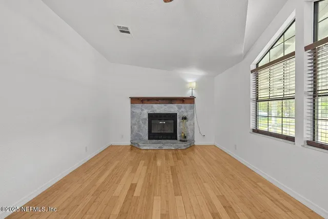 a view of an empty room with a window and fireplace