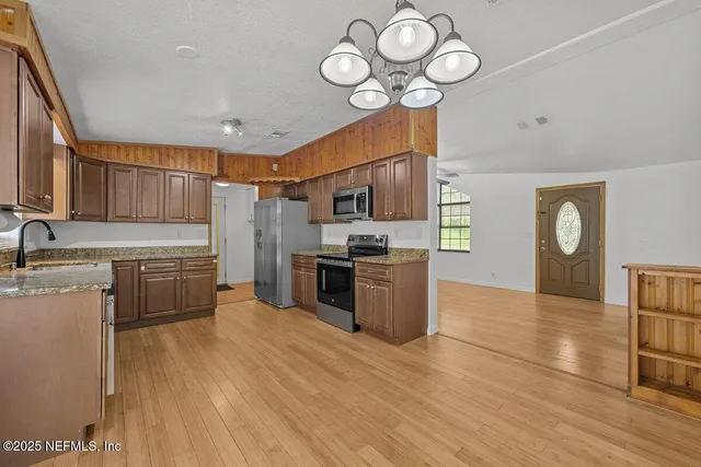 a kitchen with stainless steel appliances a stove top oven a sink cabinets and wooden floor