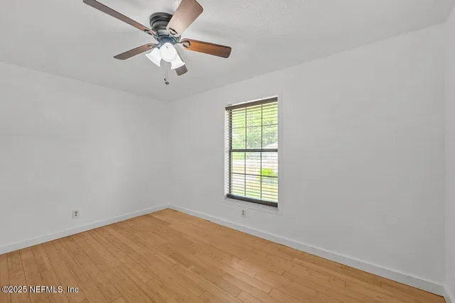 an empty room with a window and a fan