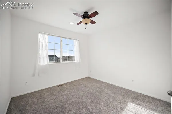 an empty room with a window and a ceiling fan