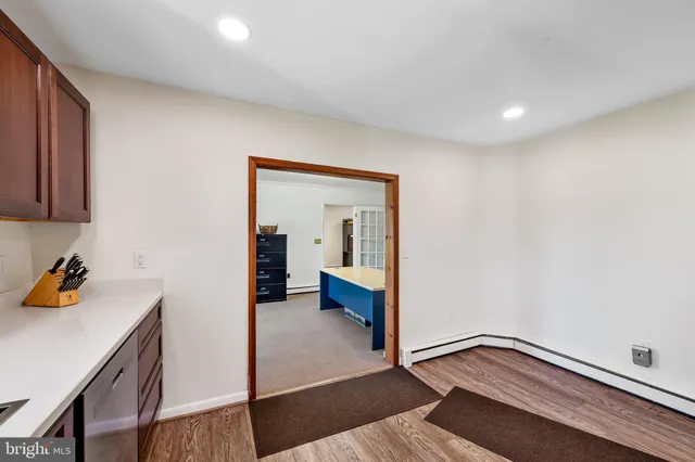 a view of a hallway to a livingroom with wooden floor and furniture