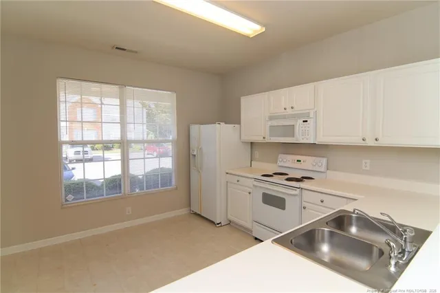 a kitchen that has a sink and white cabinets
