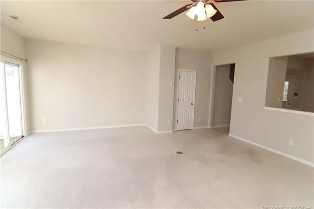 an empty room with a chandelier fan and windows