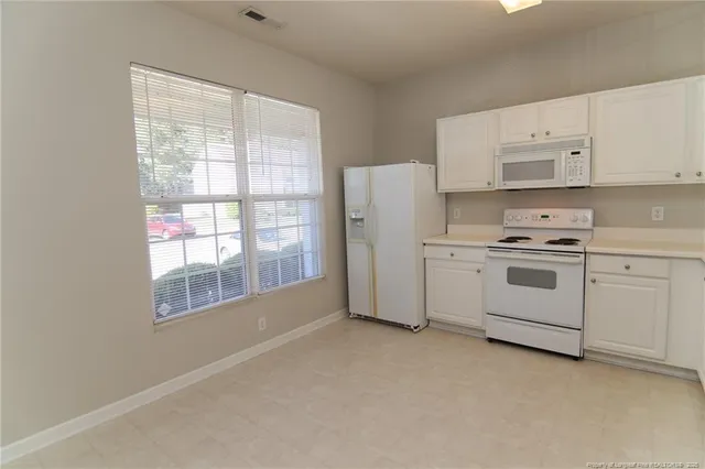 a kitchen with white cabinets and white appliances