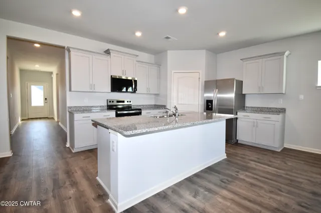 a large kitchen with stainless steel appliances granite countertop a stove a sink and a microwave