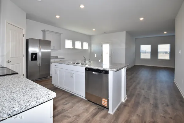 a kitchen with stainless steel appliances granite countertop a sink a stove and a refrigerator