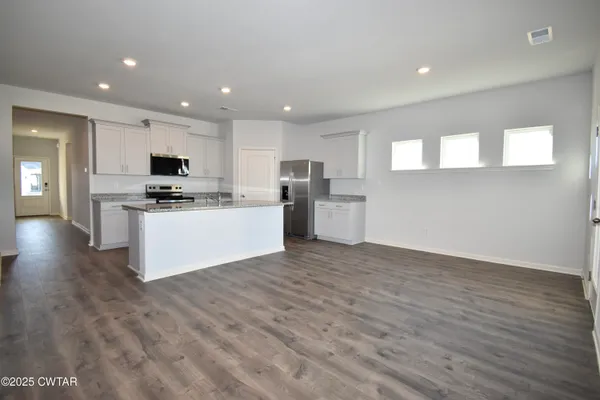 a large kitchen with stainless steel appliances granite countertop a stove a sink and a microwave