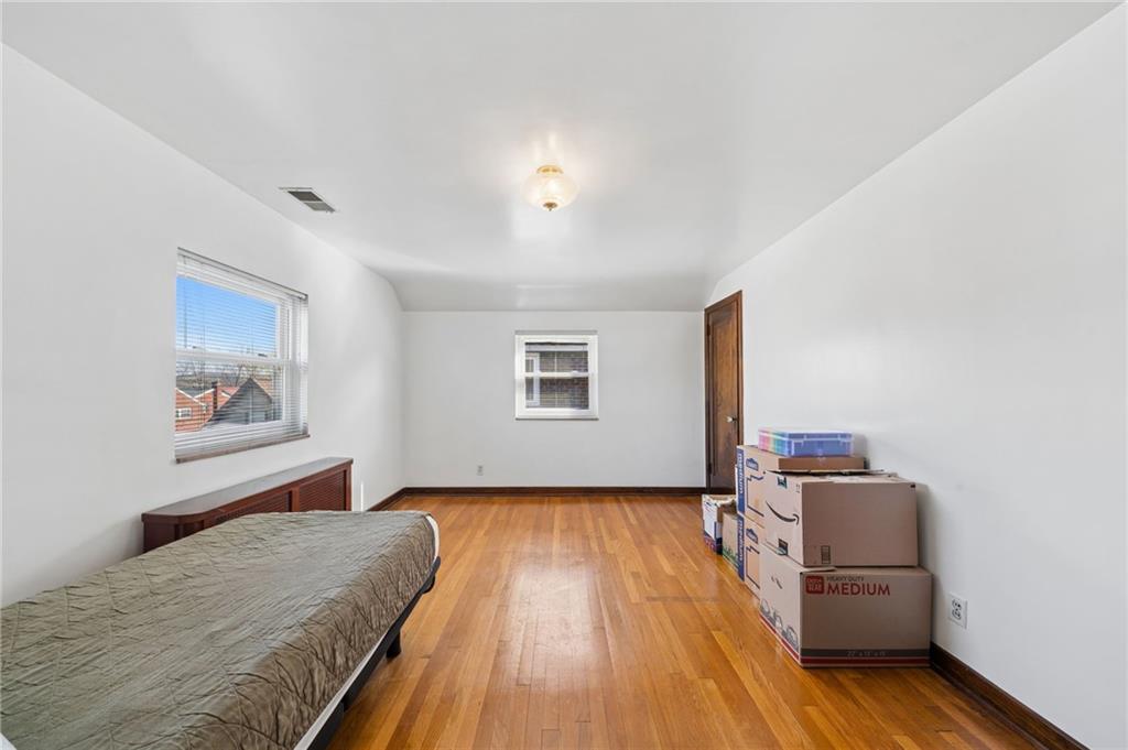 317 Raymond Street Pittsburgh, PA 15218 - Photo 19 of 36 a bedroom with a bed and wooden floor