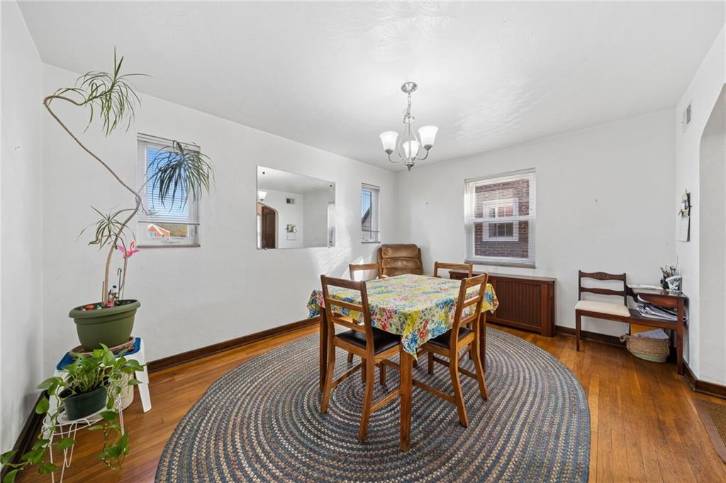 317 Raymond Street Pittsburgh, PA 15218 - Photo 10 of 36 a dining room with wooden floor a chandelier a wooden table and chairs