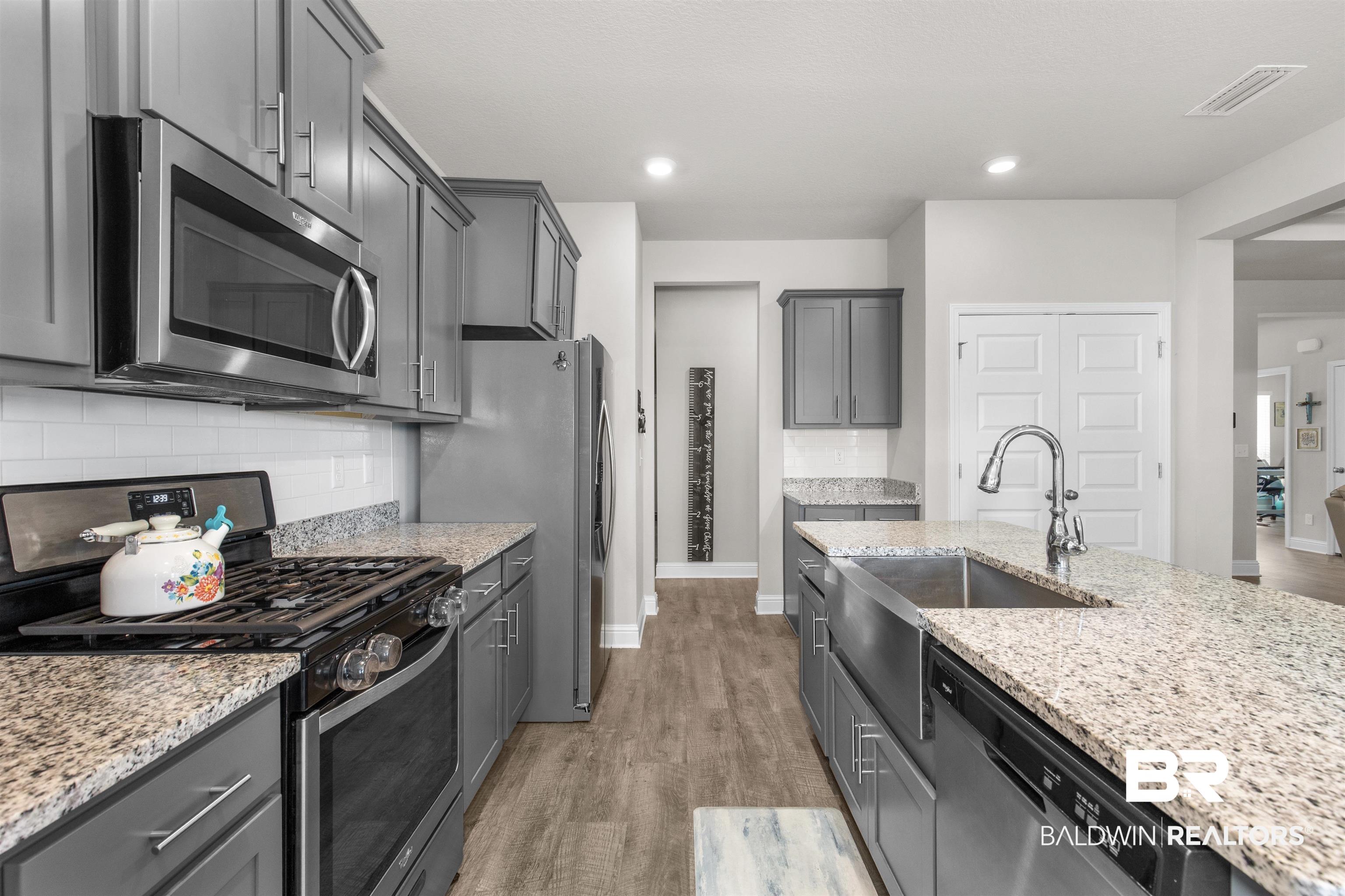 2345 Laurel Street Semmes, AL 36575 - Photo 9 of 31 Kitchen featuring appliances with stainless steel finishes, light wood-style flooring, light stone countertops, backsplash, and gray cabinets