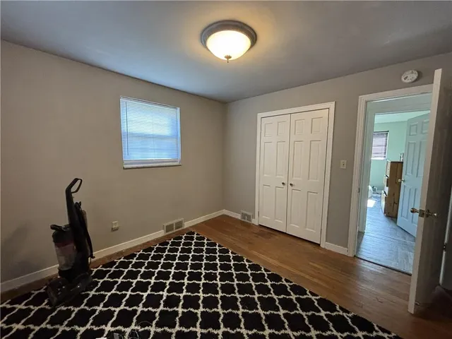 an empty room with wooden floor cabinet and a window