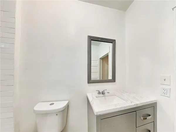 a bathroom with a toilet sink vanity and mirror