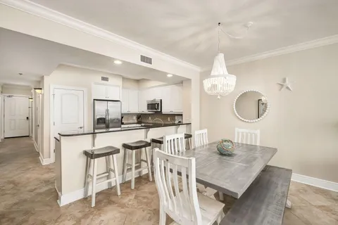 a kitchen with stainless steel appliances kitchen island granite countertop a table chairs and a refrigerator