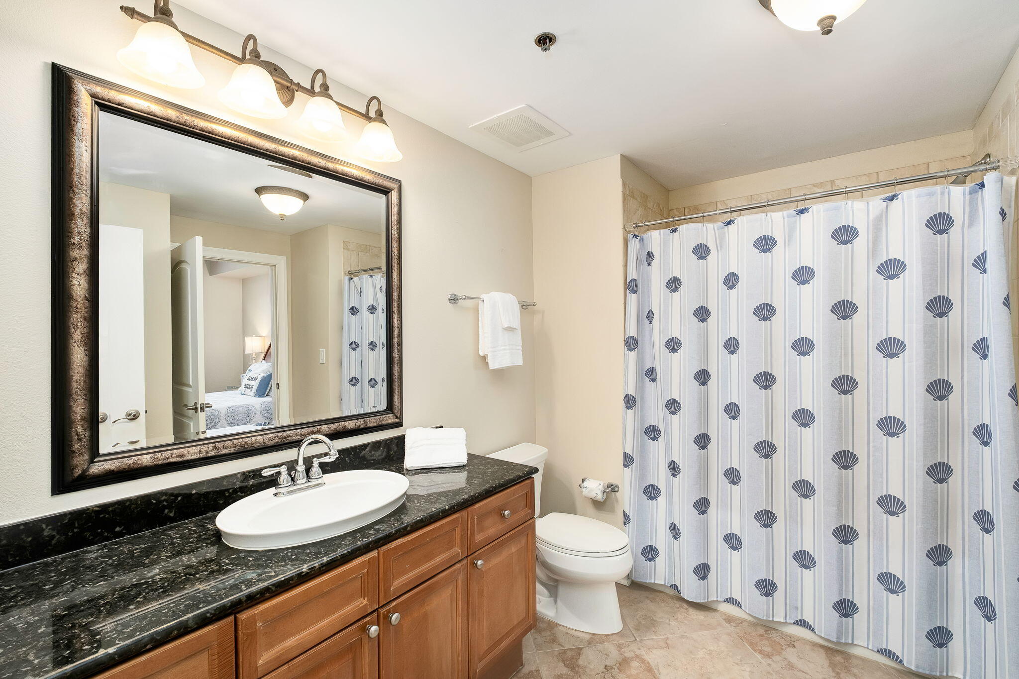 1150 Santa Rosa Boulevard, Unit 305 Fort Walton Beach, FL 32548 - Photo 24 of 43 a bathroom with a granite countertop sink a toilet a mirror a shower curtain and a large mirror