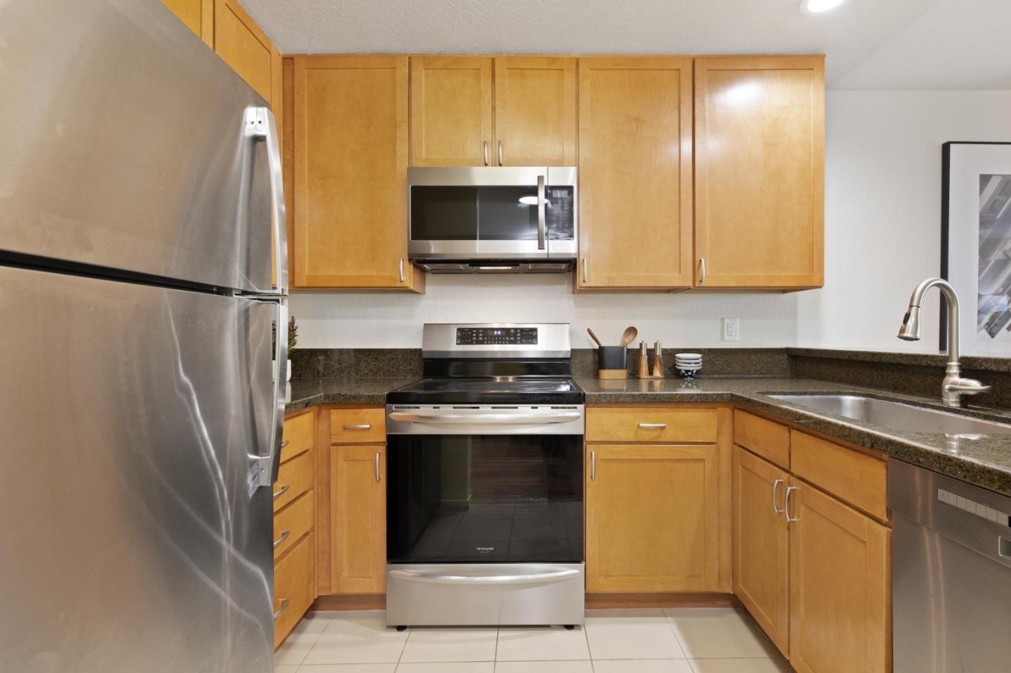 300 Murchison Drive, Unit 123 Millbrae, CA 94030 - Photo 8 of 25 a kitchen with stainless steel appliances granite countertop a stove a sink and a microwave