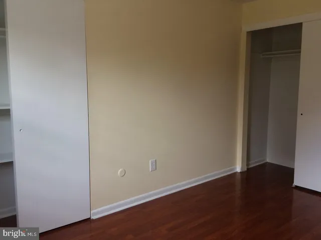 a view of an empty room with wooden floor and closet