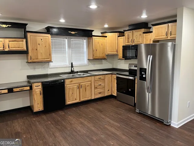 a kitchen with stainless steel appliances granite countertop a refrigerator a sink dishwasher a stove and a microwave oven on granite countertops