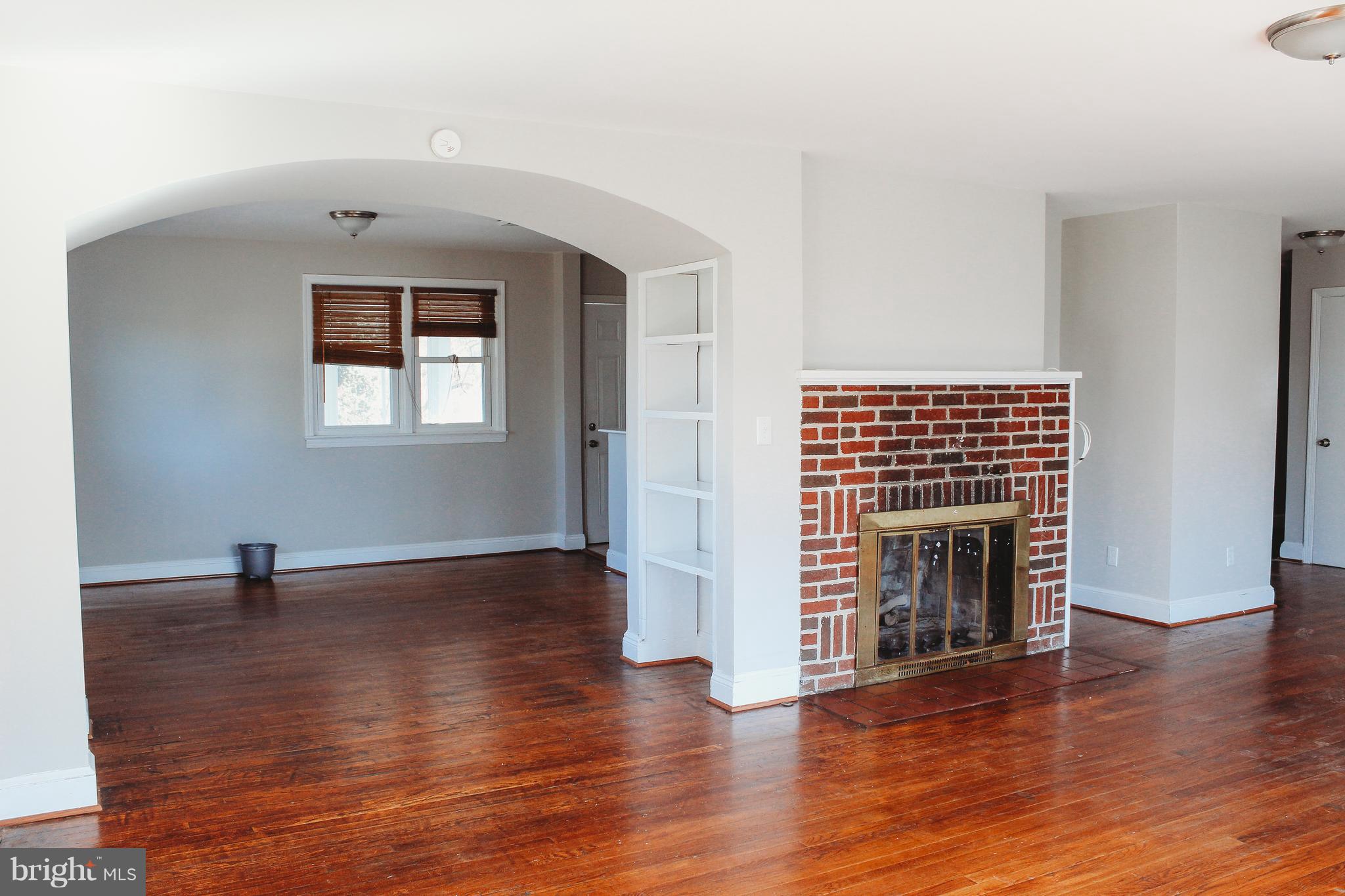 9101 Sudley Road Manassas, VA 20110 - Photo 8 of 19 an empty room with wooden floor fireplace and windows