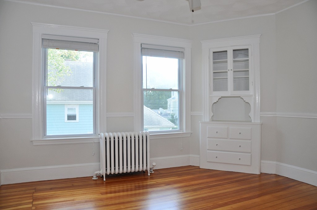 135-137 Thacher Street, Unit 2 Milton, MA 02186 - Photo 5 of 11 an empty room with wooden floor and windows