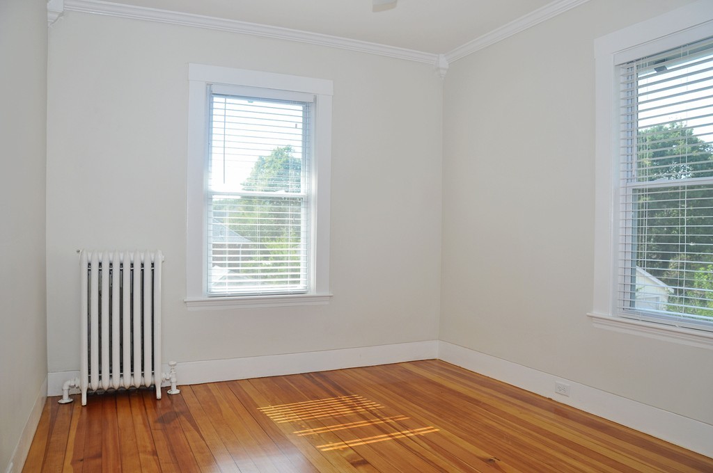 135-137 Thacher Street, Unit 2 Milton, MA 02186 - Photo 10 of 11 an empty room with wooden floor and windows