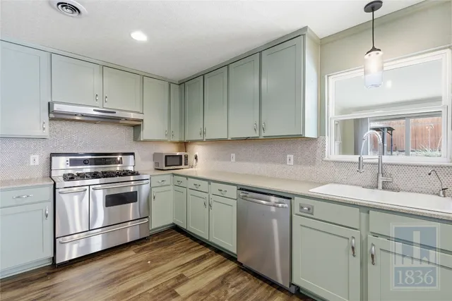 a kitchen with a sink cabinets and wooden floor