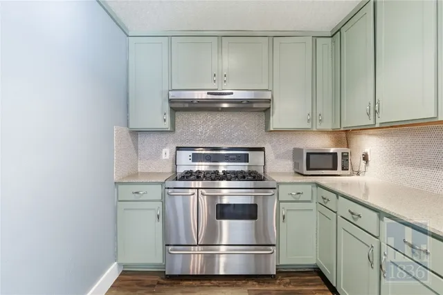 a kitchen with granite countertop white cabinets and white stove