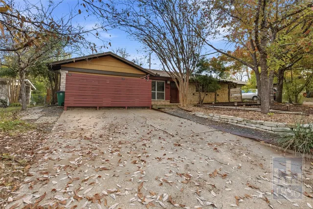 a backyard of a house with large trees and a wooden fence