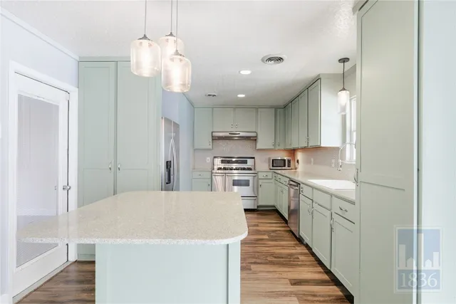 a kitchen with stainless steel appliances a refrigerator a sink dishwasher a stove and white cabinets with wooden floor