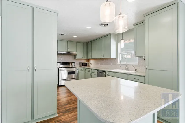 a kitchen with stainless steel appliances granite countertop a sink a stove and a refrigerator