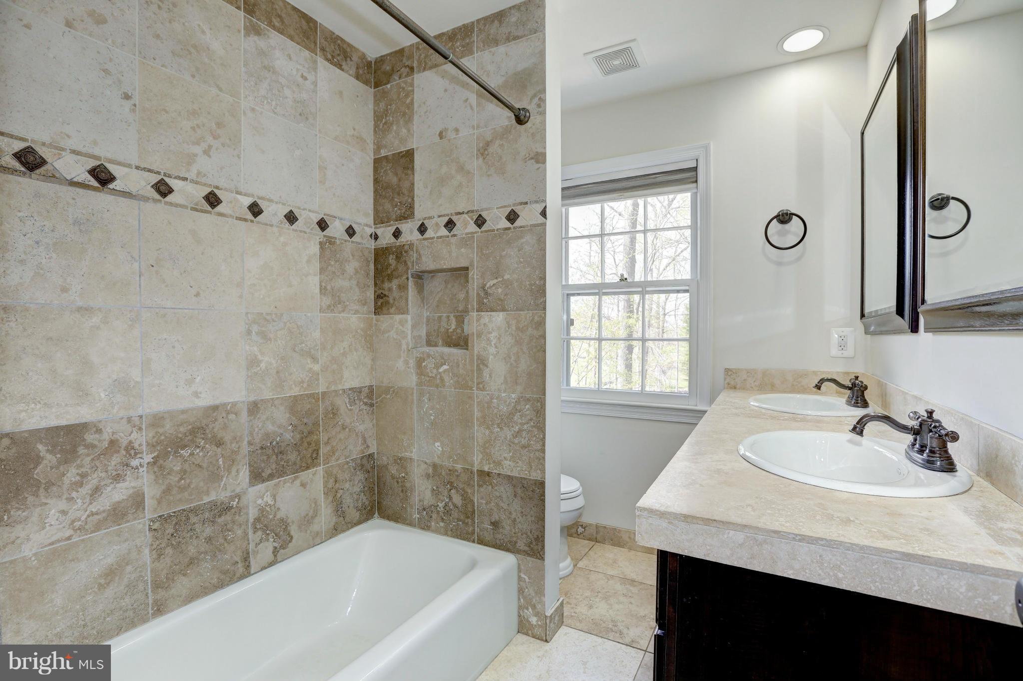 13116 Brandon Way Road Gaithersburg, MD 20878 - Photo 16 of 30 a bathroom with a granite countertop sink a mirror a bathtub and shower