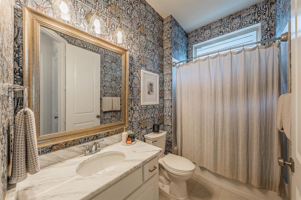 1205 Ivy Charm Way Arlington, TX 76005 - Photo 6 of 40 Bathroom featuring patterned wallpaper, a white vanity with an integrated sink, a large framed mirror, and a window with a shower curtain