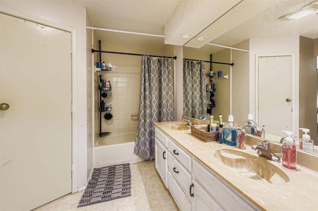 6232 North Ridge Road Fort Worth, TX 76135 - Photo 14 of 29 a bathroom with a double vanity sink a mirror a bathtub and shower