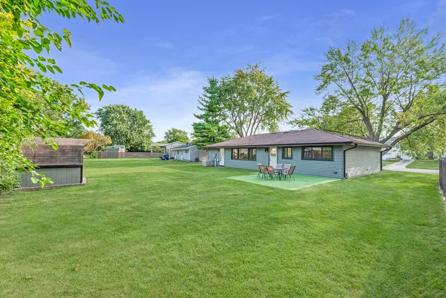 a view of a house with a big yard potted plants and large tree