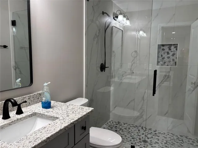 a bathroom with a granite countertop sink toilet a shower and a mirror