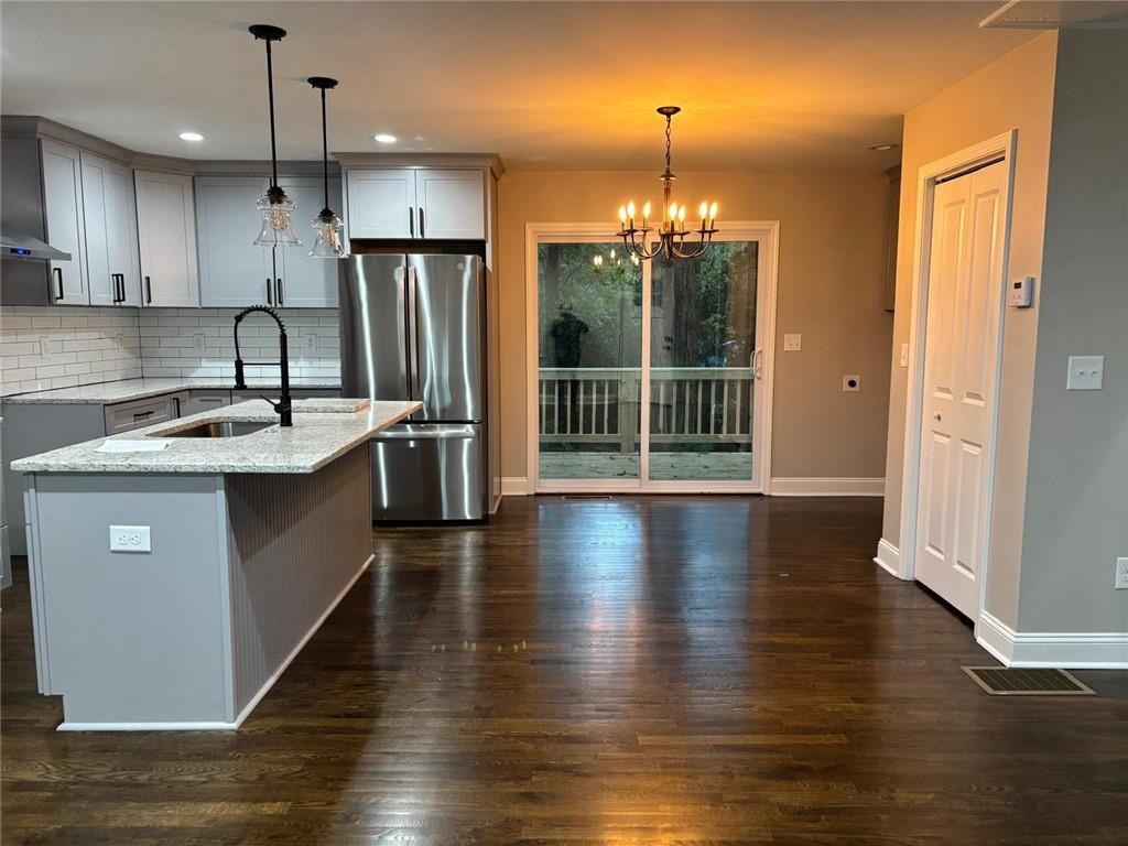 2485 Ortega Way Chamblee, GA 30341 - Photo 15 of 27 a kitchen with stainless steel appliances granite countertop a refrigerator a sink dishwasher a stove and a dining table with wooden floor