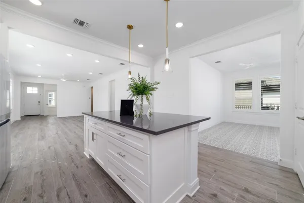 a kitchen with stainless steel appliances granite countertop wooden floors and view of living room