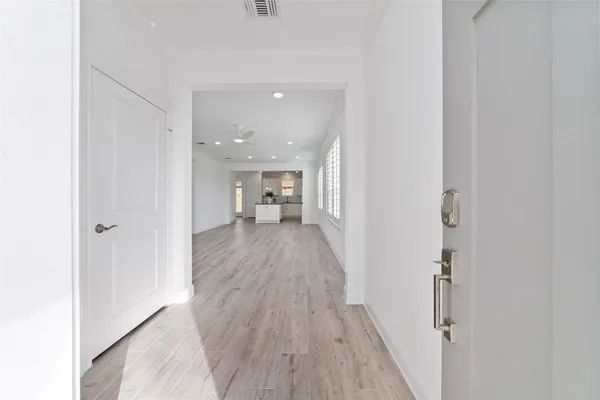 a view of a hallway with wooden floor and a bathroom