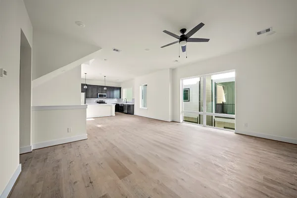 a view of a livingroom with a hardwood floor a ceiling fan and windows