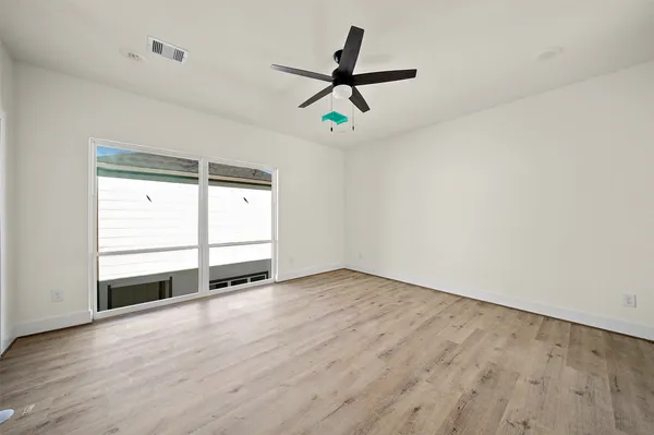 a view of empty room with wooden floor and ceiling fan
