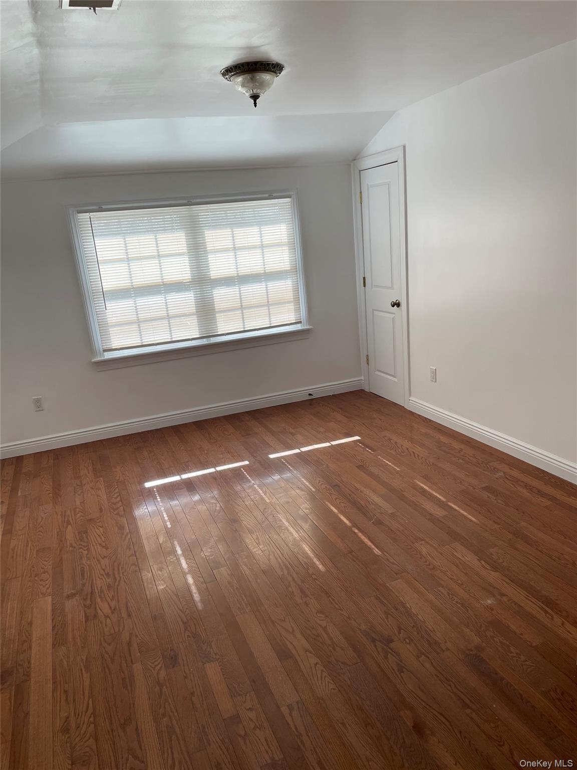 64-57 230th Street Queens, NY 11364 - Photo 6 of 7 an empty room with wooden floor and windows