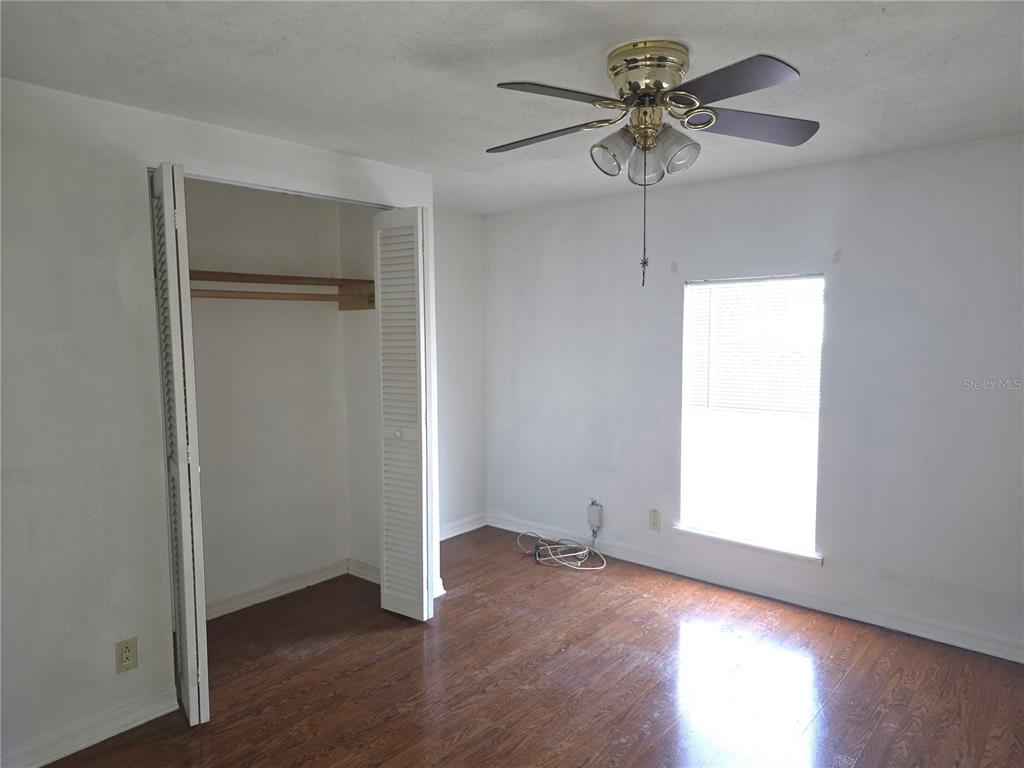 6525 Tralee Avenue New Port Richey, FL 34653 - Photo 7 of 11 an empty room with wooden floor and a ceiling fan