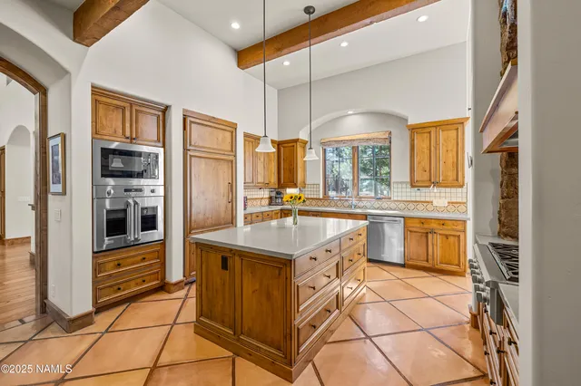 a kitchen with stainless steel appliances granite countertop a table chairs and a refrigerator