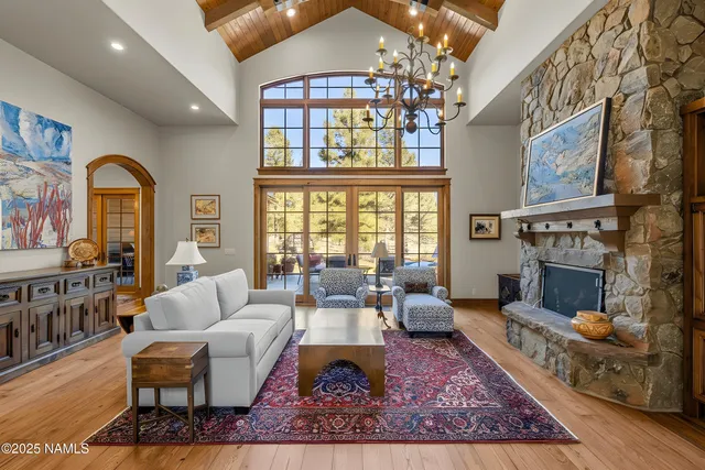 a living room with furniture large windows and wooden floor