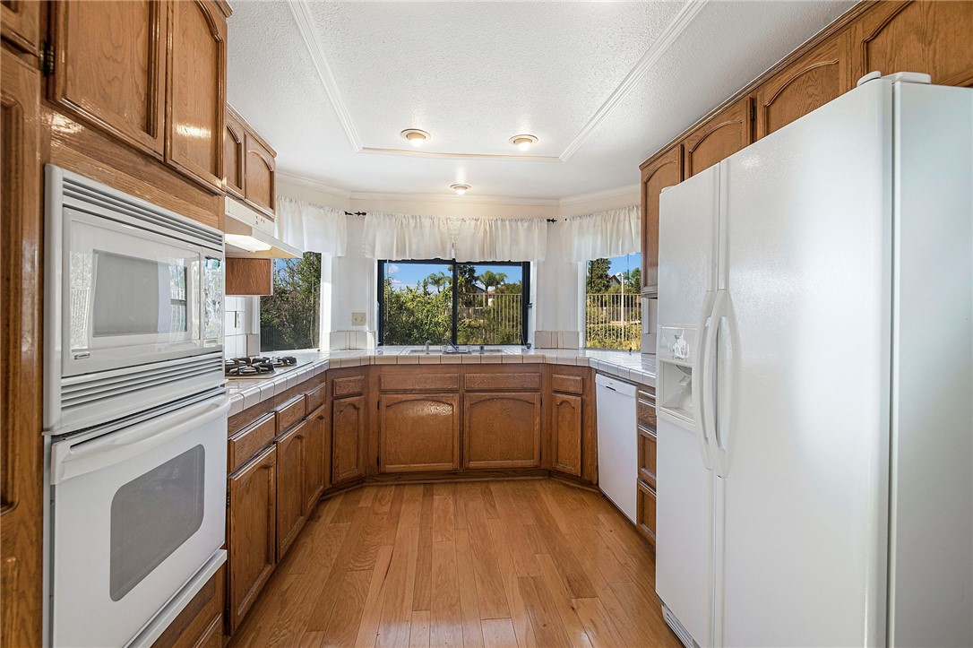 12065 Crystal Glen Way Porter Ranch, CA 91326 - Photo 14 of 38 a kitchen with stainless steel appliances granite countertop a refrigerator a sink dishwasher a stove and white countertops with wooden floor
