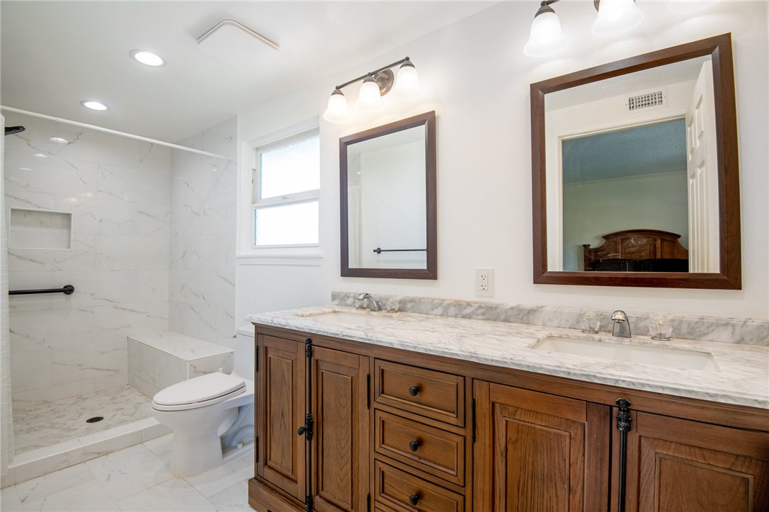 12065 Crystal Glen Way Porter Ranch, CA 91326 - Photo 19 of 38 a bathroom with a granite countertop sink toilet a large mirror a bathtub and shower