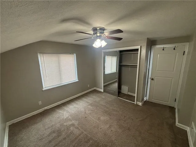 an empty room with closet and a ceiling fan