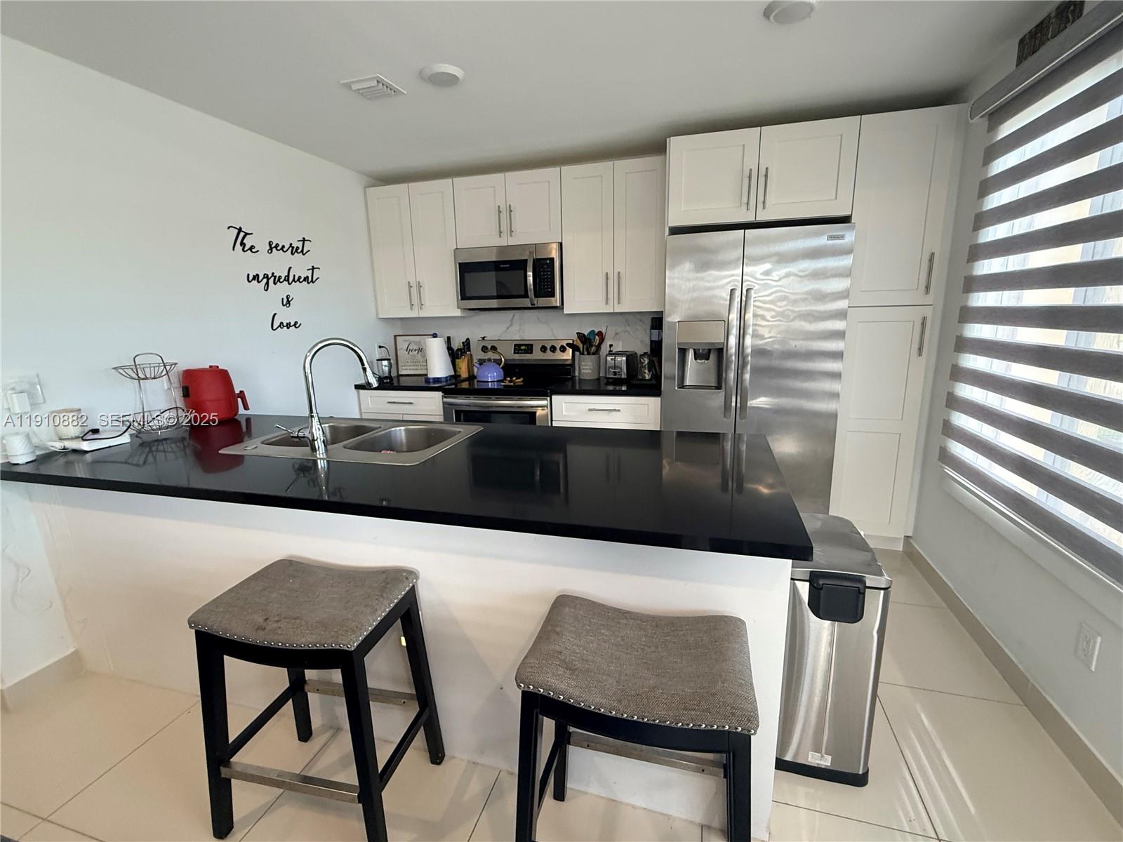 25855 Southwest 139th Court Homestead, FL 33032 - Photo 6 of 23 a kitchen with stainless steel appliances a dining table chairs refrigerator and sink