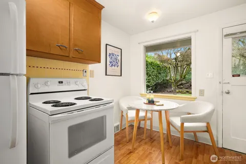 a kitchen with stainless steel appliances kitchen island a table chairs in it and wooden floors