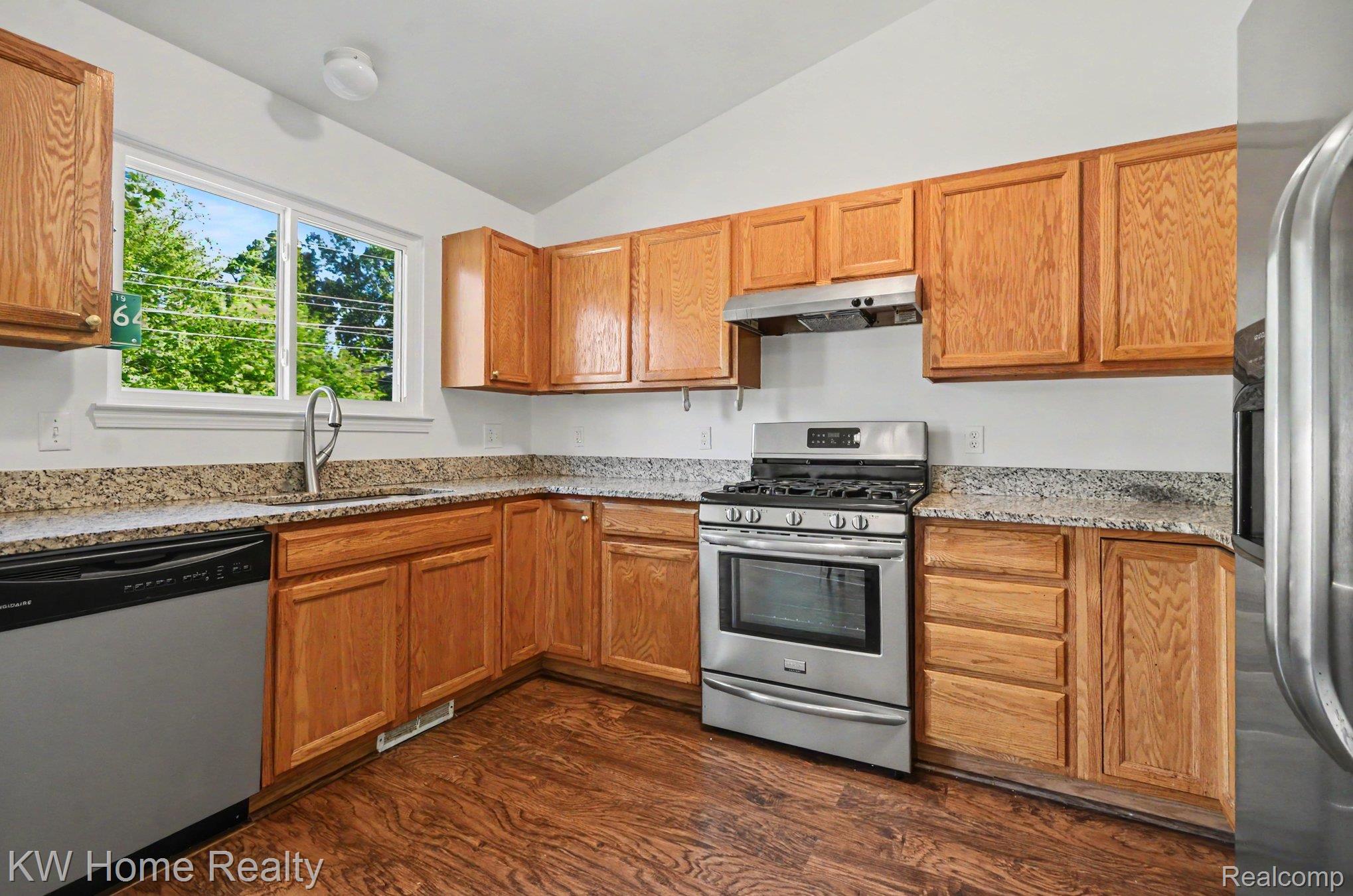 2383 East Maple Road Troy, MI 48083 - Photo 5 of 25 Kitchen featuring wood cabinetry, light-toned granite-style countertops, stainless steel appliances, and wood-finish flooring
