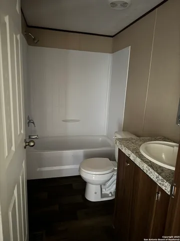 a bathroom with a granite countertop sink a toilet a mirror and shower